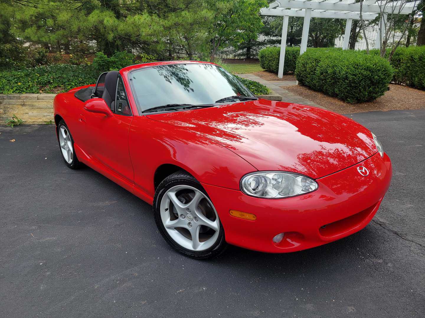 A red mazda mx-5 roadster is parked in a parking lot.