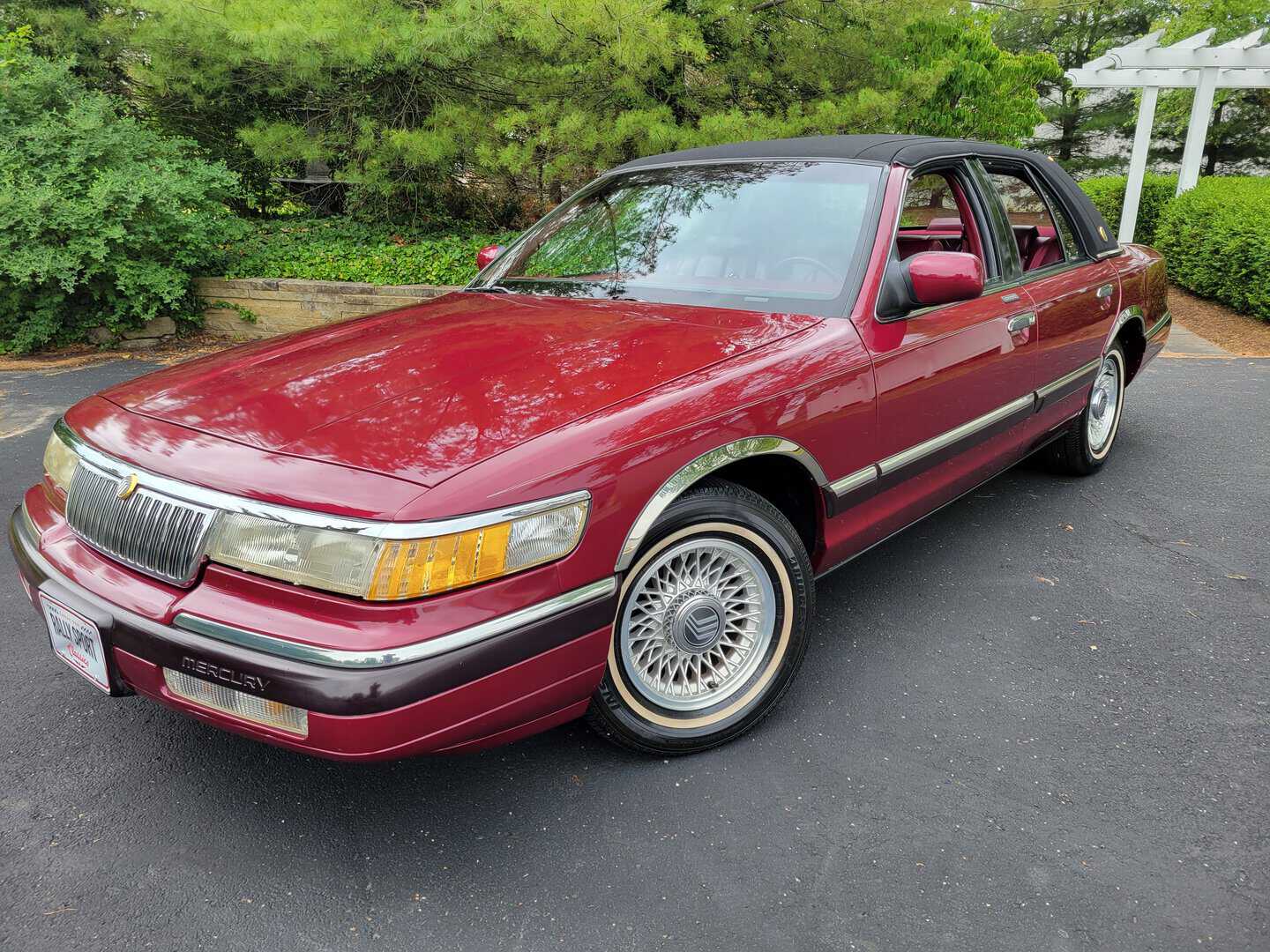 A maroon lincoln town car is parked in a parking lot.