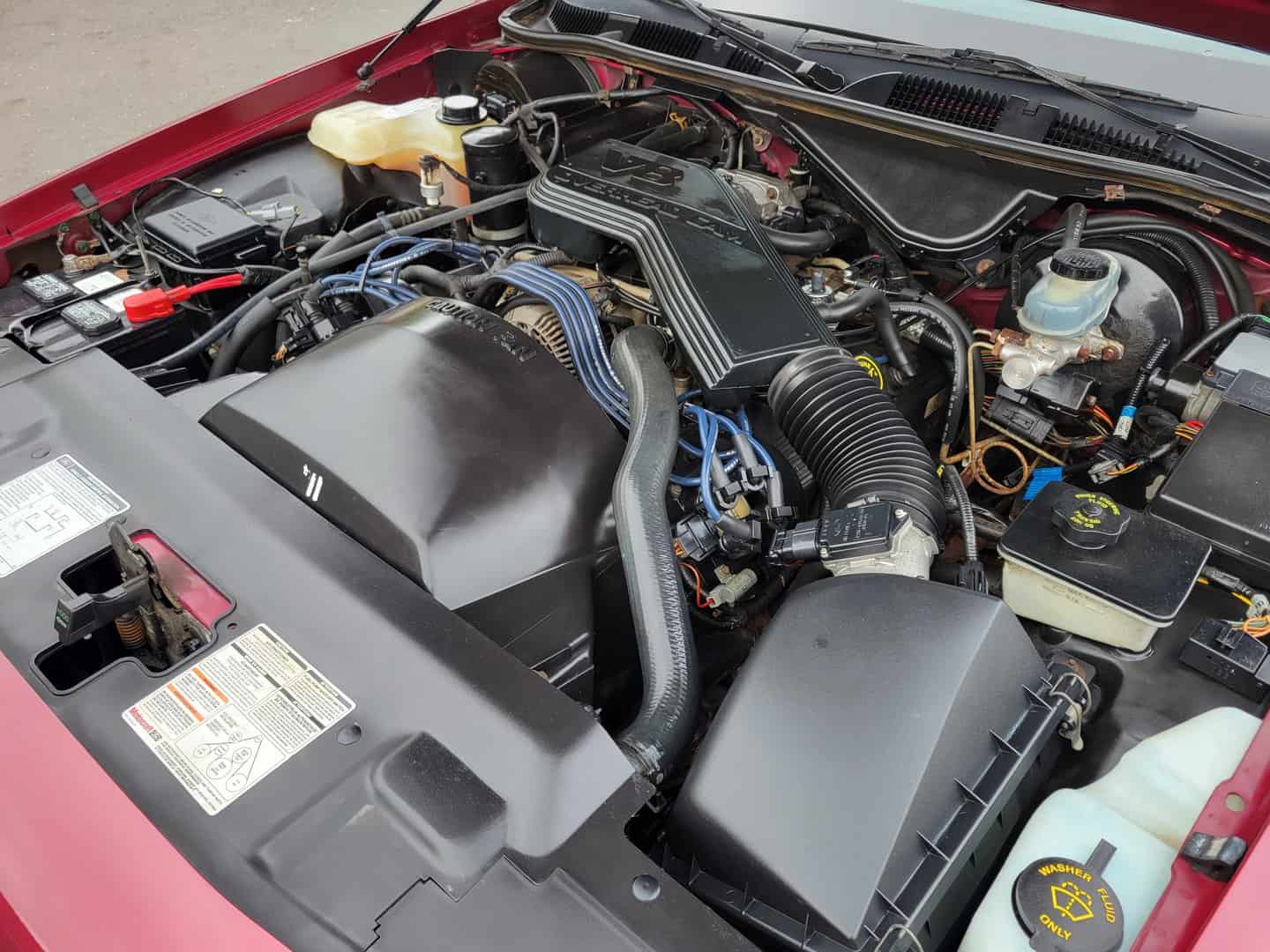 The engine compartment of a red car.