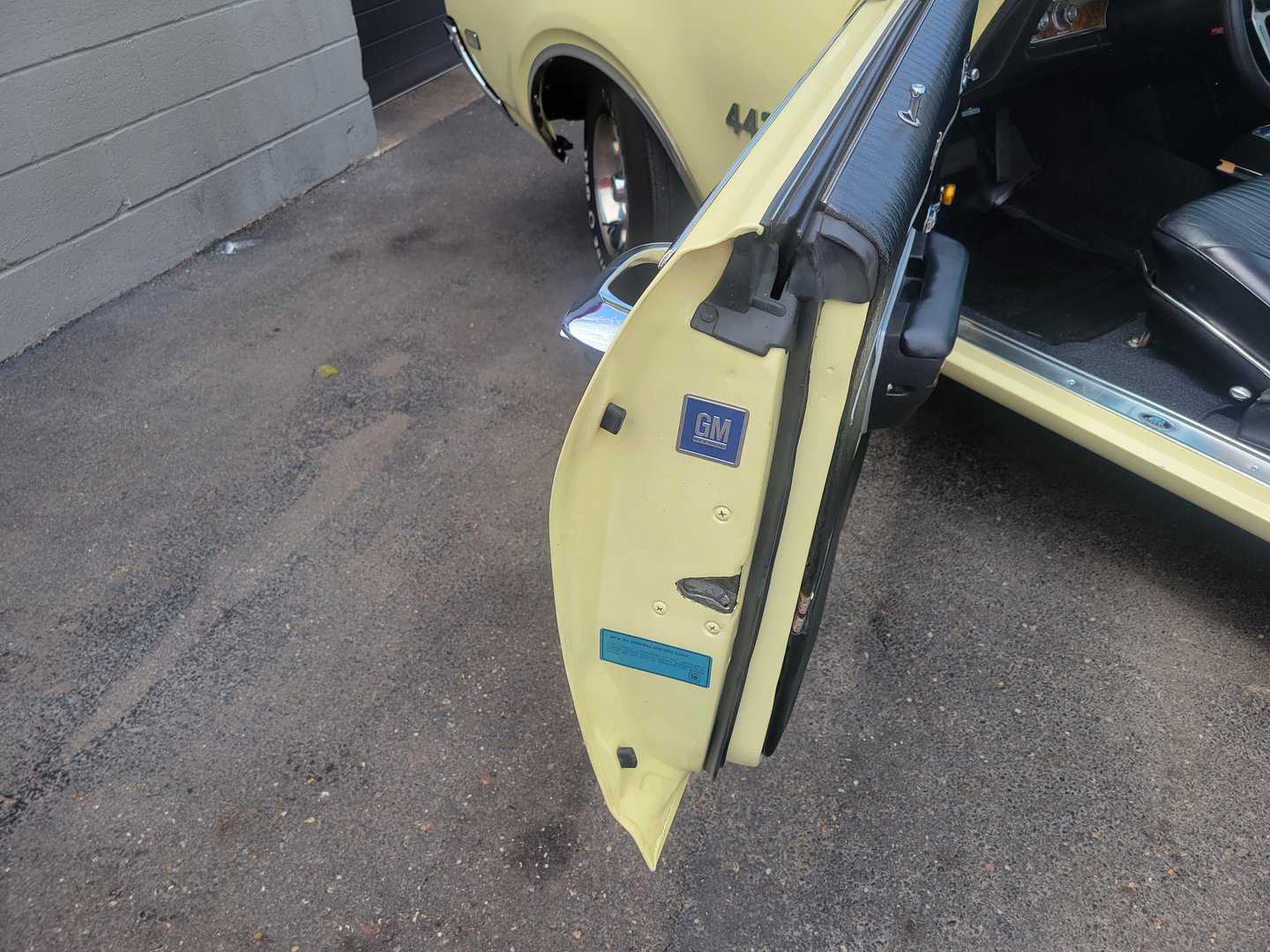The door of a yellow 1969 Oldsmobile 442 car is open.