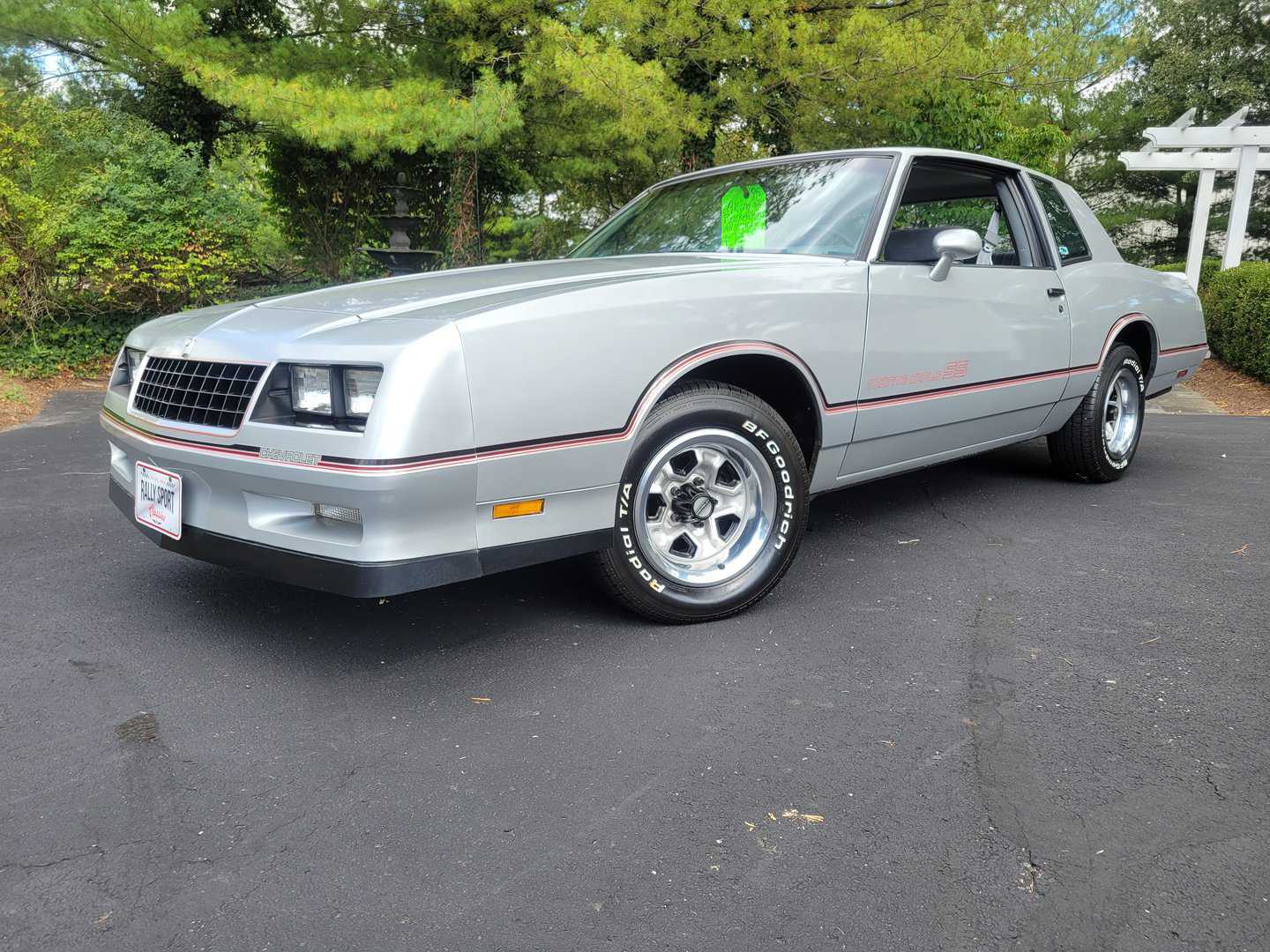 A silver Chevrolet Camaro parked in a parking lot adjacent to a 1985 Monte Carlo SS.