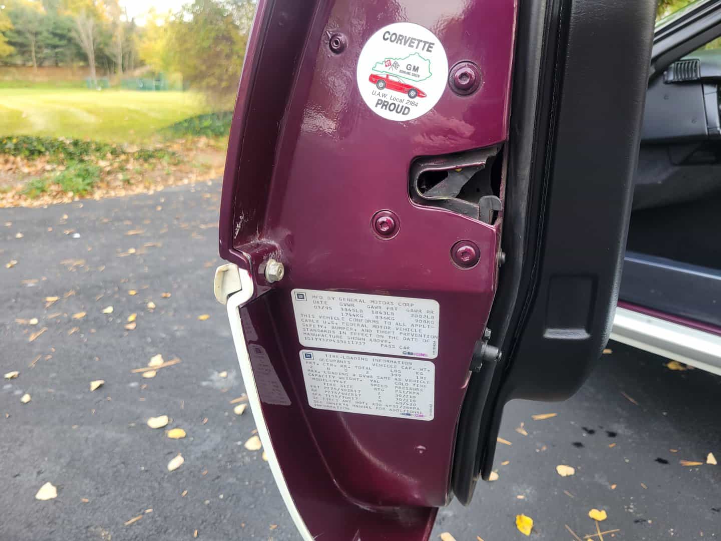 The door handle of a maroon 1995 Corvette Pace Car with a sticker on it.