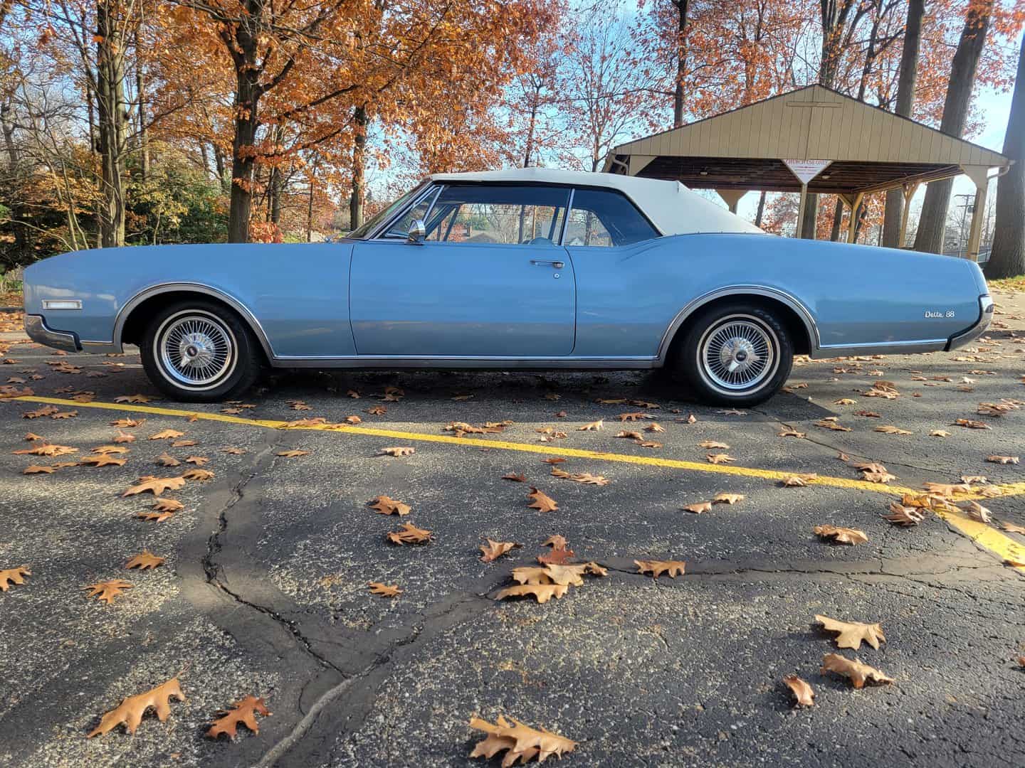 A 1967 Oldsmobile, An Old Blue Car, Parked In A Parking Lot.