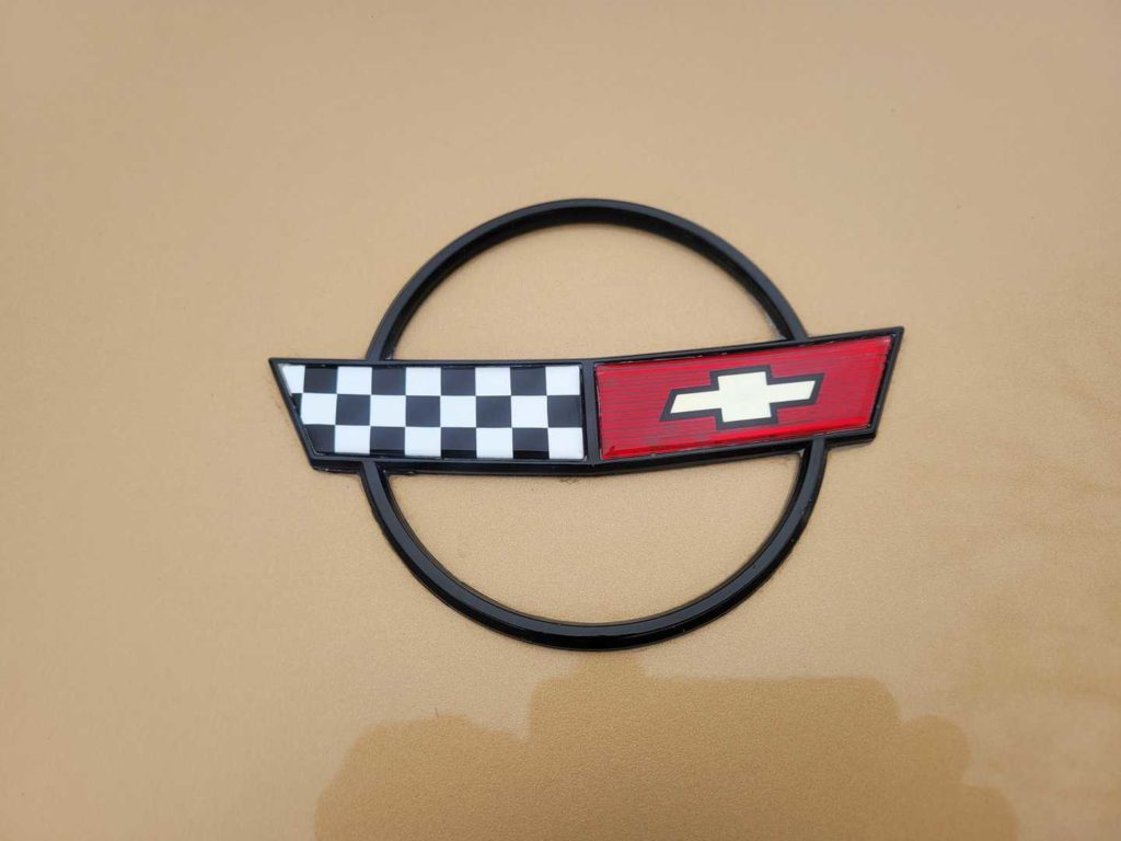A 1986 Chevrolet Corvette Emblem With A Checkered Pattern On It.