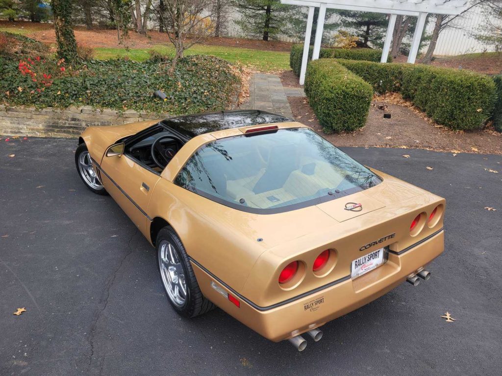 A 1986 Gold Chevrolet Corvette, A Classic Coupe, Parked In A Driveway.