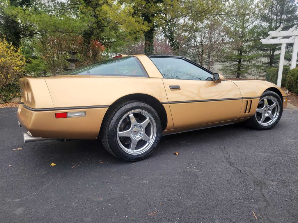 A 1986 Gold Chevrolet Corvette Coupe Parked In A Driveway.