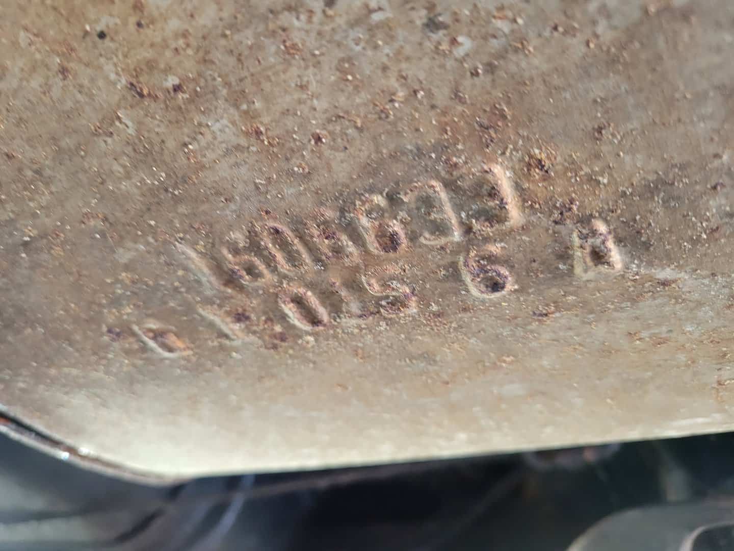 A Rusty Piece Of Metal With A Number On It From A 1976 Cadillac Coupe Deville.