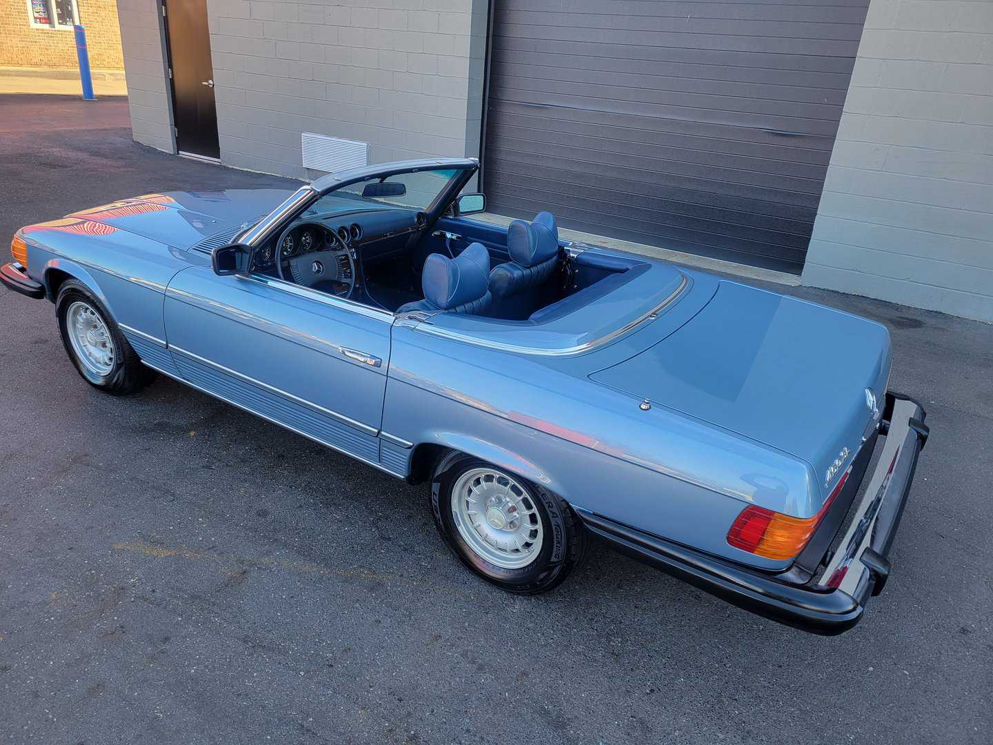 A Blue Mercedes Benz 450 Sl Convertible Parked In Front Of A Garage.