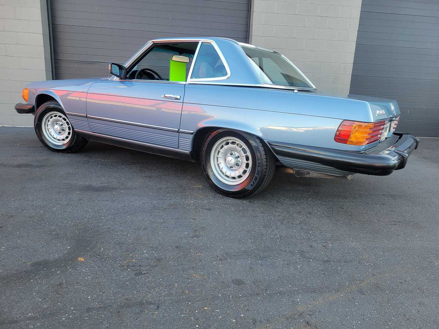 A Blue Mercedes Benz 450 Sl Is Parked In Front Of A Garage.