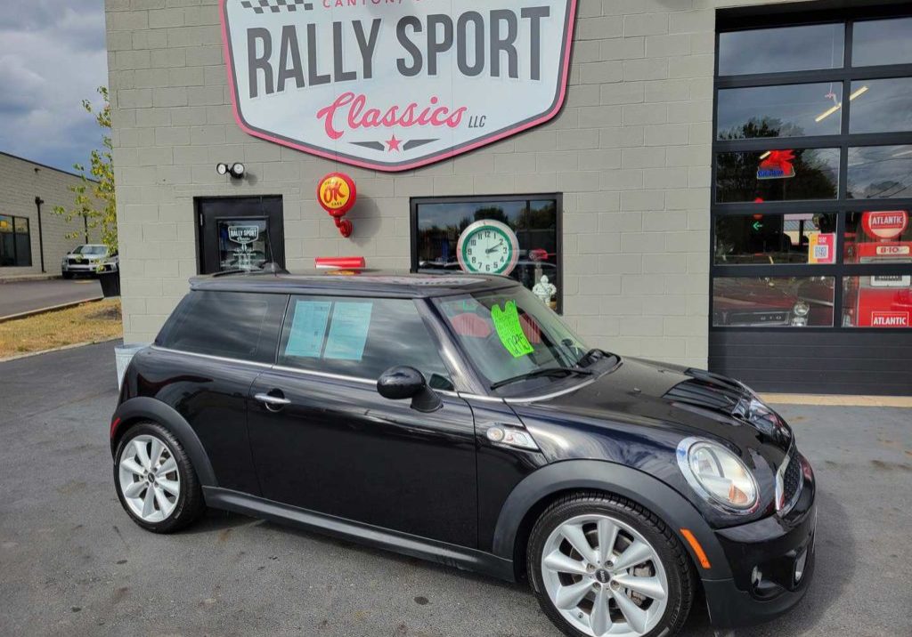 A 2013 black Mini Cooper S parked in front of a rally sport.