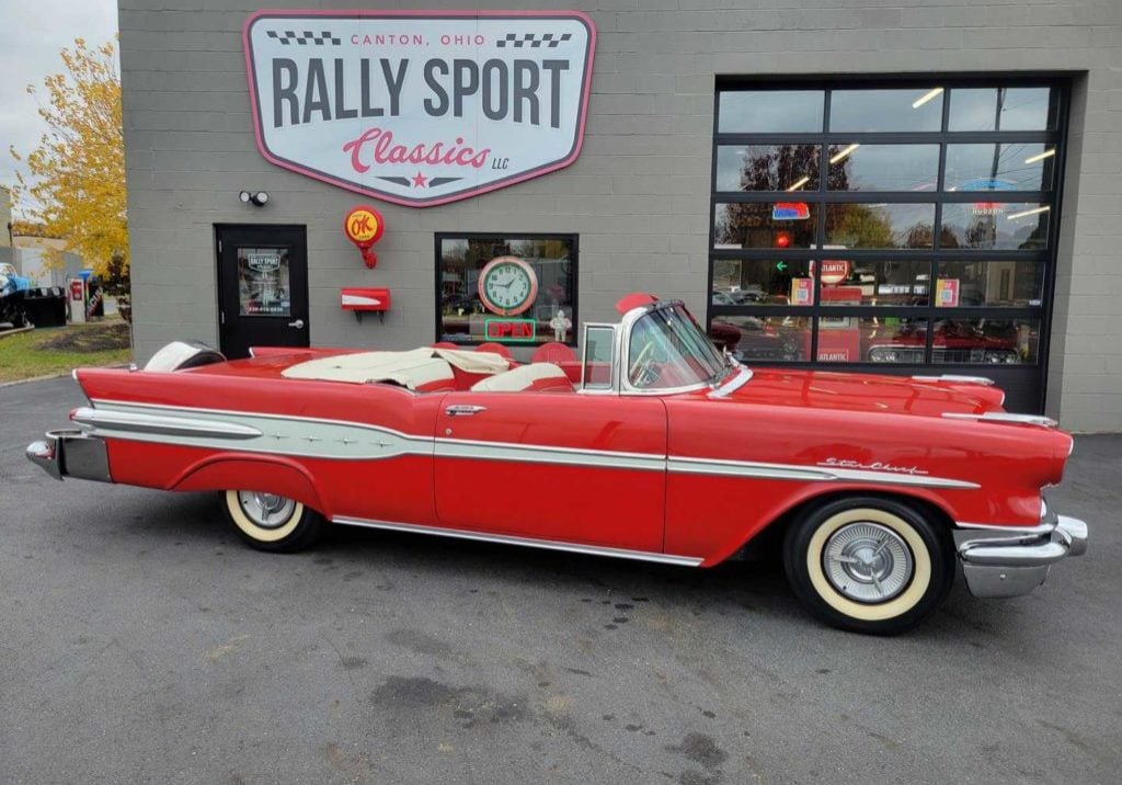 A Red Pontiac Starchief Convertible, Parked In Front Of A Rally Sport Classic Car Shop.
